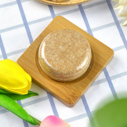 Luonnollinen yrttishampoo palamuodossa, vihreä, kasvuun ja hoitoon, ympärillä yrttejä ja kukkia.